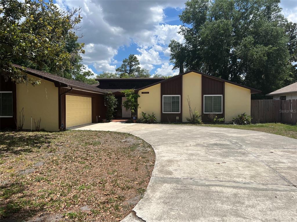 A single-story house with a yellow stucco exterior, brown trim, and a concrete driveway — 4576 NORTH LANE, ORLANDO, FL