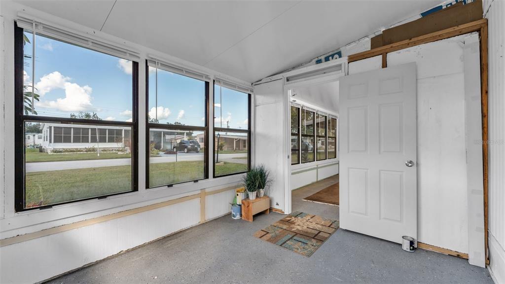 A sunroom with gray flooring, white walls, and large windows looking out onto a neighborhood — 203 JANET LANE, LAKELAND, FL