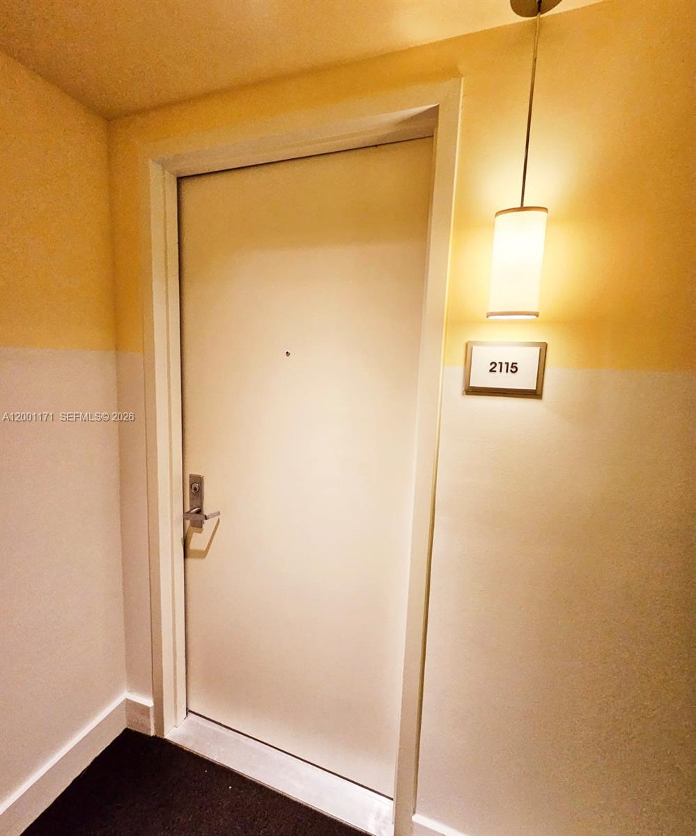A white apartment door with a room number sign and a hanging light fixture — 475 Brickell Ave # 2115, Miami FL 33131, MIAMI, FL