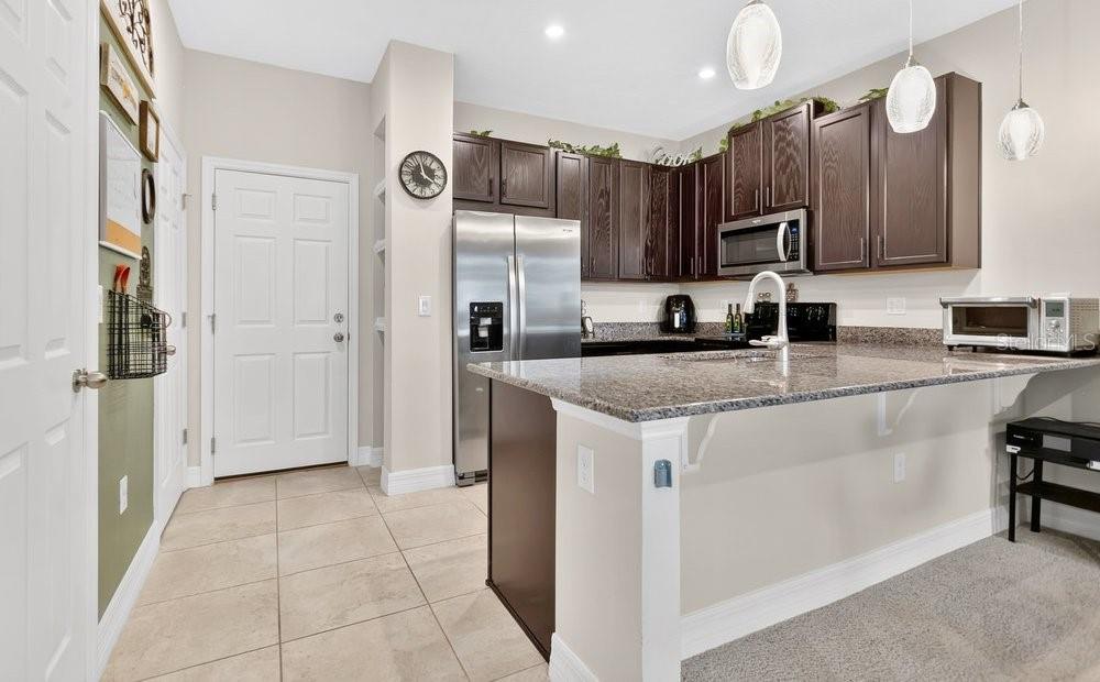 A kitchen with dark wood cabinets, stainless steel appliances, and a granite-topped breakfast bar — 2145 VALENCIA BLOSSOM STREET, CLERMONT, FL