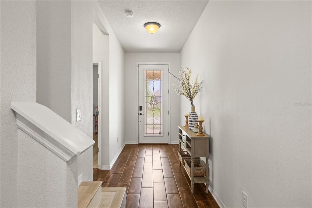 A bright entryway features wood-look tile flooring, a glass-paneled front door, and a console table — 12476 TIBBETTS STREET, ODESSA, FL