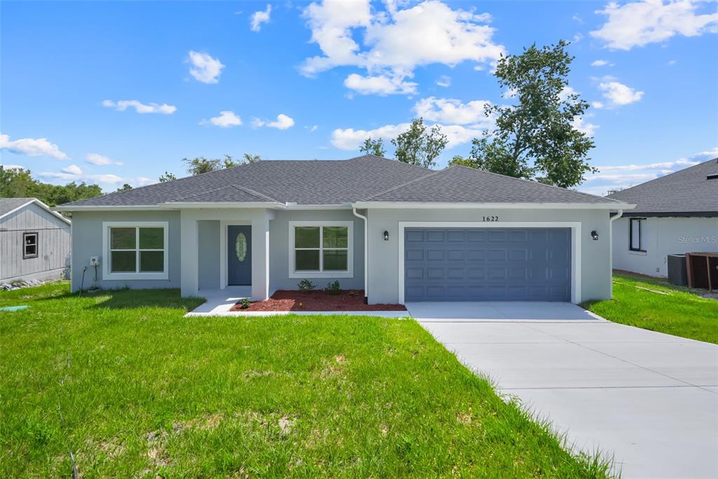 A single-story house with a gray exterior, a two-car garage, and a concrete driveway — 1622 N MERRICK DRIVE, DELTONA, FL