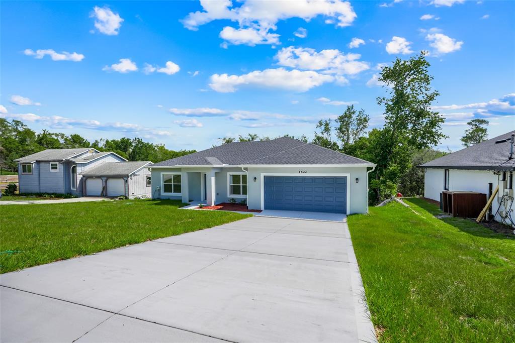 A single-story house with a gray exterior, blue garage door, and a concrete driveway — 1622 N MERRICK DRIVE, DELTONA, FL