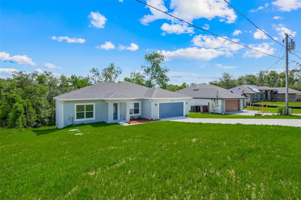 A single-story light gray house with a two-car garage sits on a grassy lot — 1622 N MERRICK DRIVE, DELTONA, FL