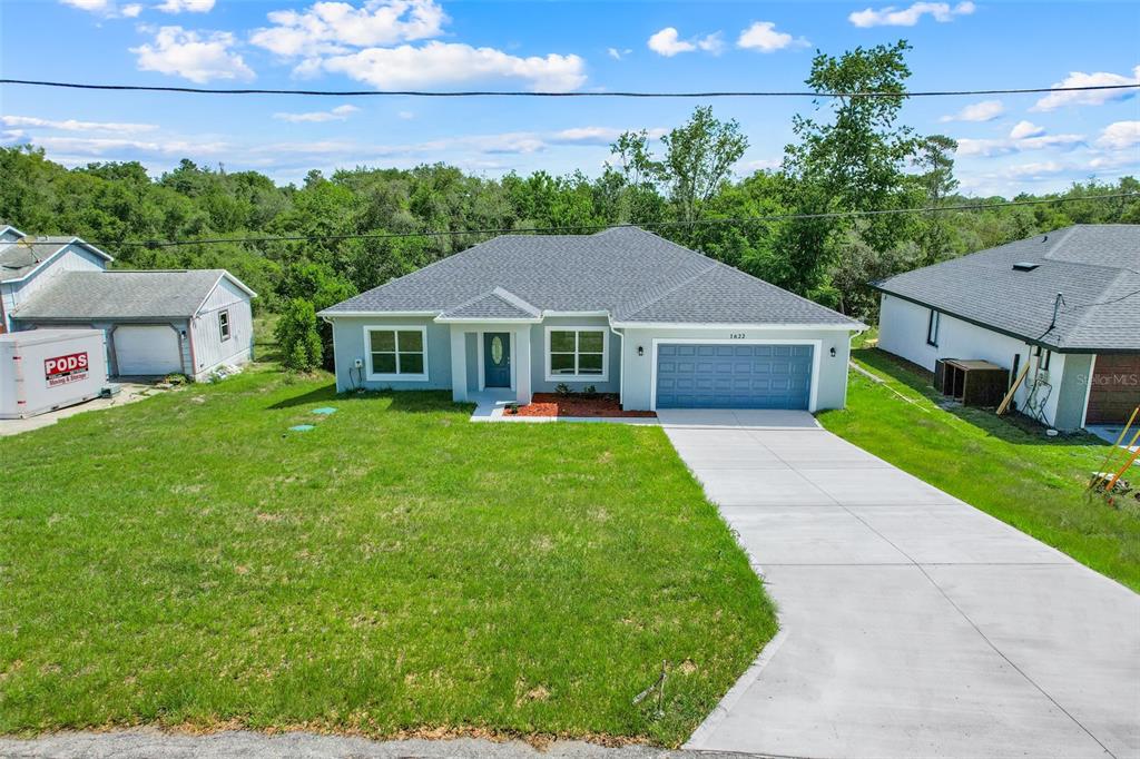 A single-story house with a blue garage door, gray roof, and a concrete driveway — 1622 N MERRICK DRIVE, DELTONA, FL