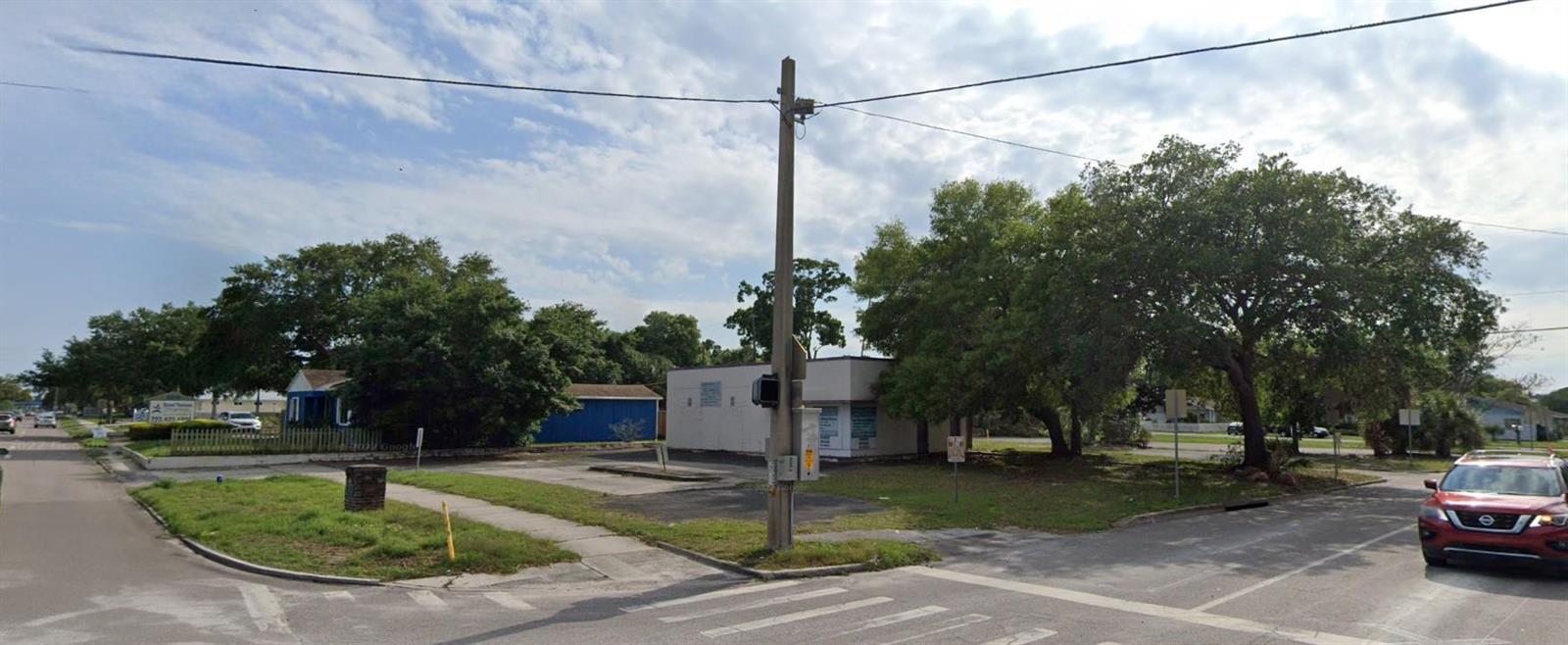 A corner lot features a small commercial building, a blue shed, and several mature trees — 1246 N 16th Street, FL 33705, FL