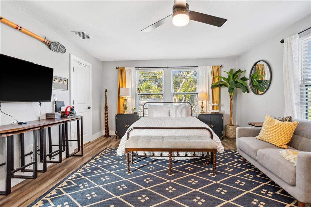 A bedroom features a bed with white bedding, a round mirror, and a gray sofa — 4015 10TH AVENUE N UNIT B, ST PETERSBURG, FL