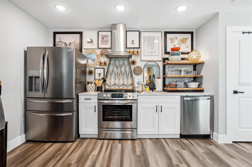 A kitchen features stainless steel appliances, white cabinetry, wood-look flooring, and a gallery wall — 4015 10TH AVENUE N UNIT B, ST PETERSBURG, FL