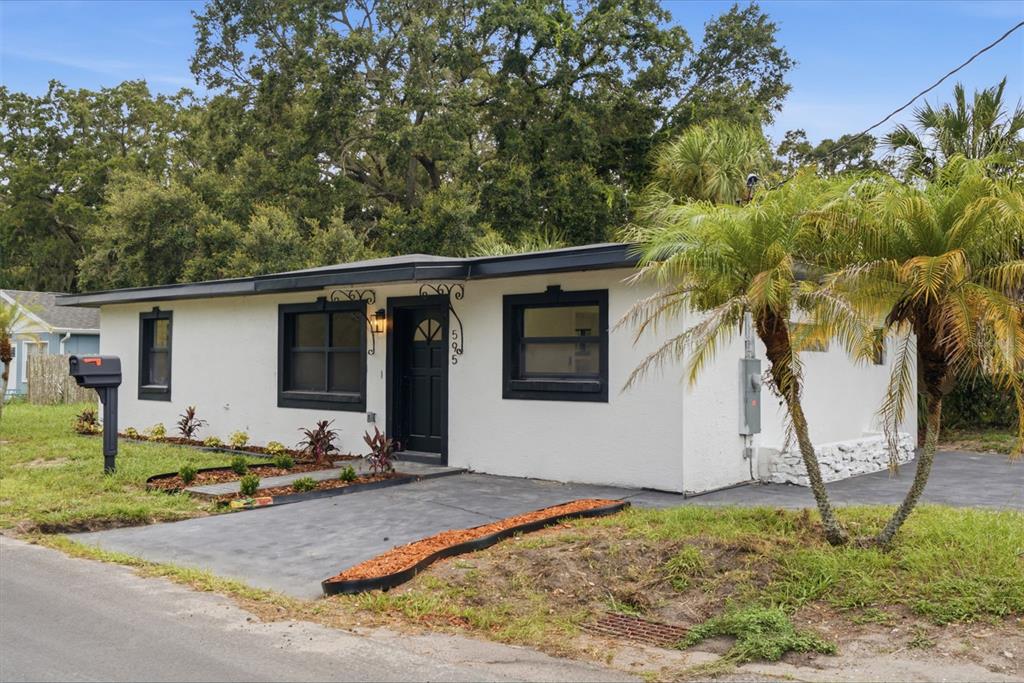 A white single-story house with a black door, black window frames, and a paved driveway — 595 PINE STREET, SAFETY HARBOR, FL