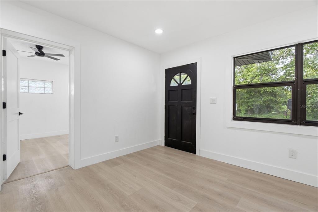 A room with light wood-look flooring, white walls, a black door, and a window — 595 PINE STREET, SAFETY HARBOR, FL