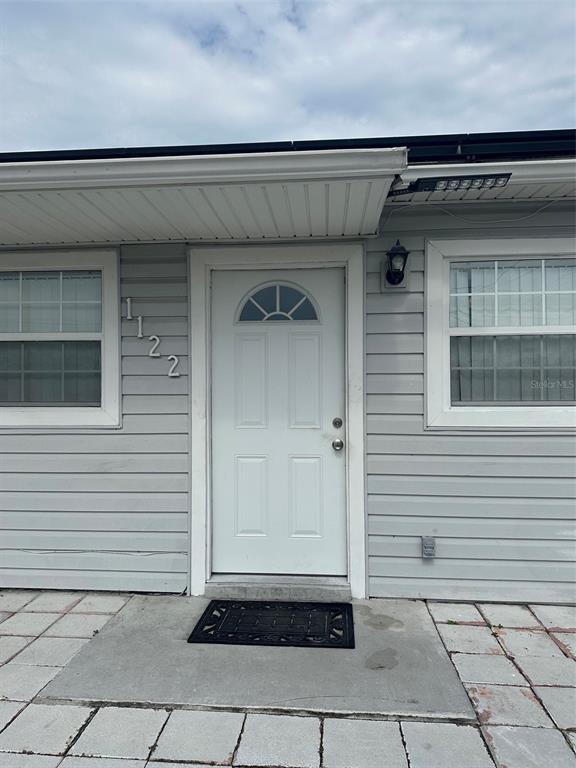 A white front door with a small arched window is centered on a light gray-sided exterior — 1122 OVERDALE STREET, ORLANDO, FL