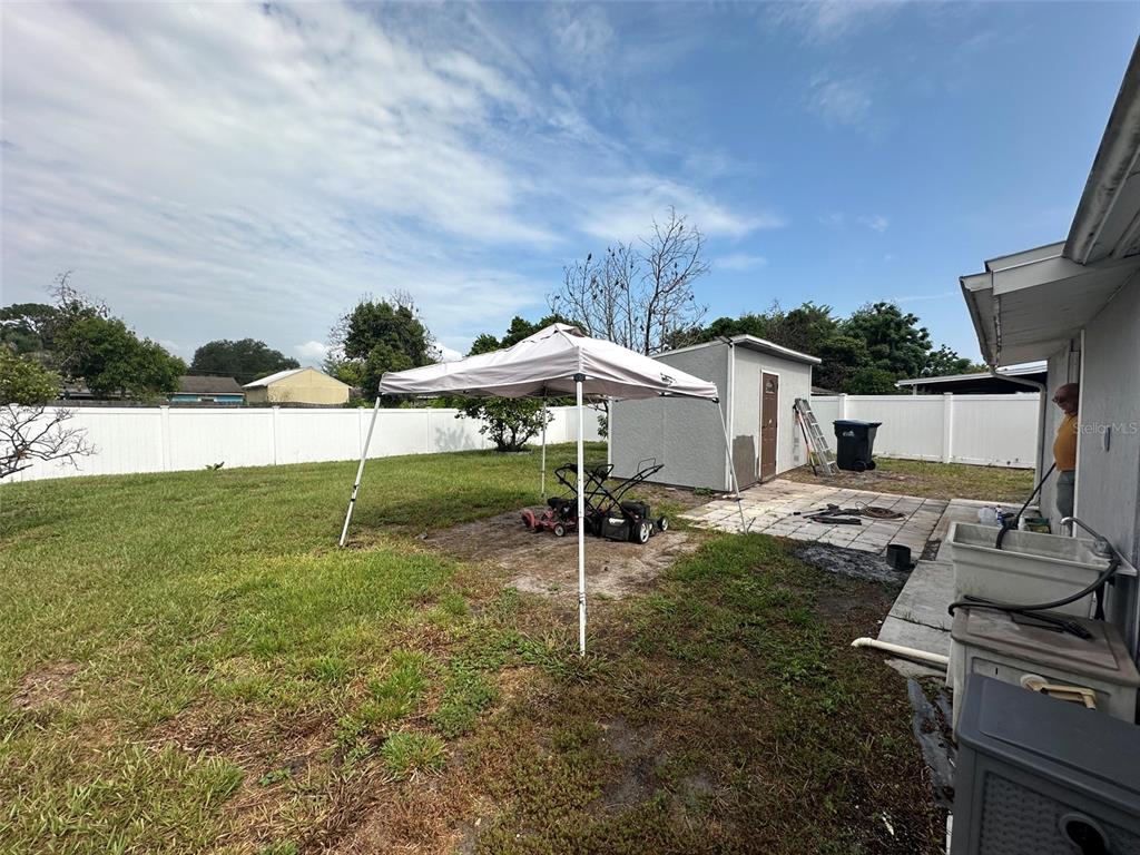 A backyard features a white pop-up canopy, a small storage shed, and a white fence — 1122 OVERDALE STREET, ORLANDO, FL