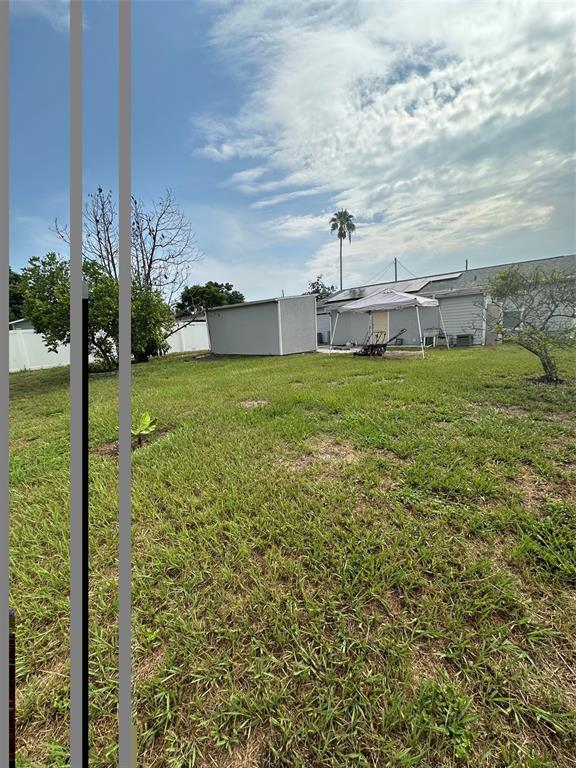 A backyard features a grassy lawn, a storage shed, a pop-up canopy, and a palm tree — 1122 OVERDALE STREET, ORLANDO, FL