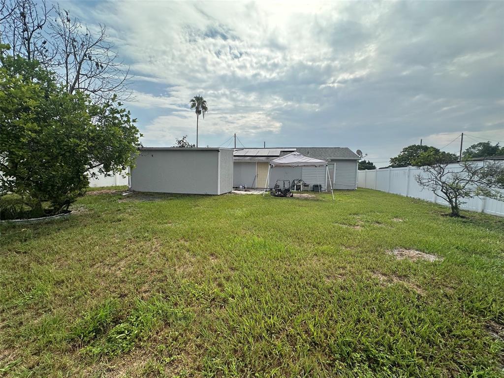 A backyard features a house with solar panels, a detached shed, and a white fence — 1122 OVERDALE STREET, ORLANDO, FL