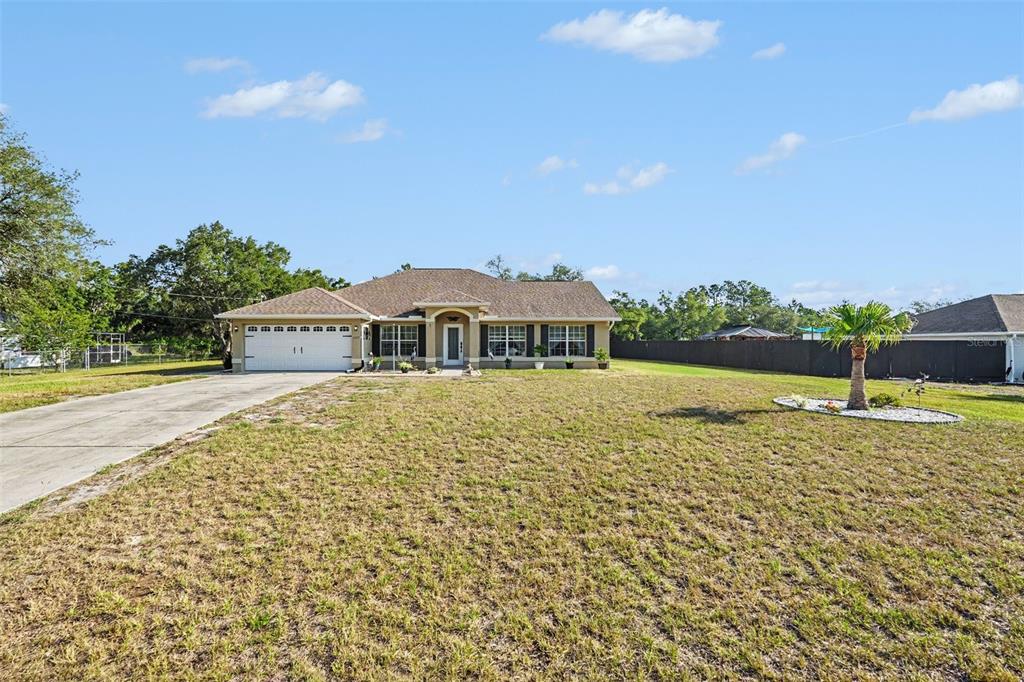 A living room features a beige sofa, two green armchairs, and a wooden coffee table — 11177 MIRAGE AVENUE, BROOKSVILLE, FL
