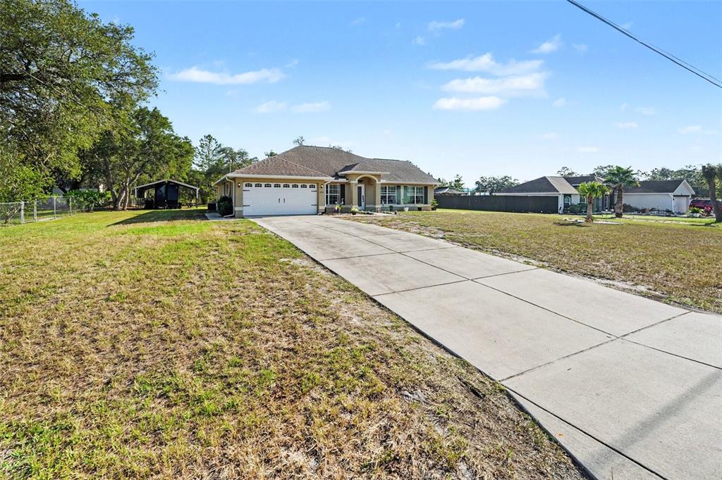 A bright living room features neutral furniture, a television, and a front entry door — 11177 MIRAGE AVENUE, BROOKSVILLE, FL