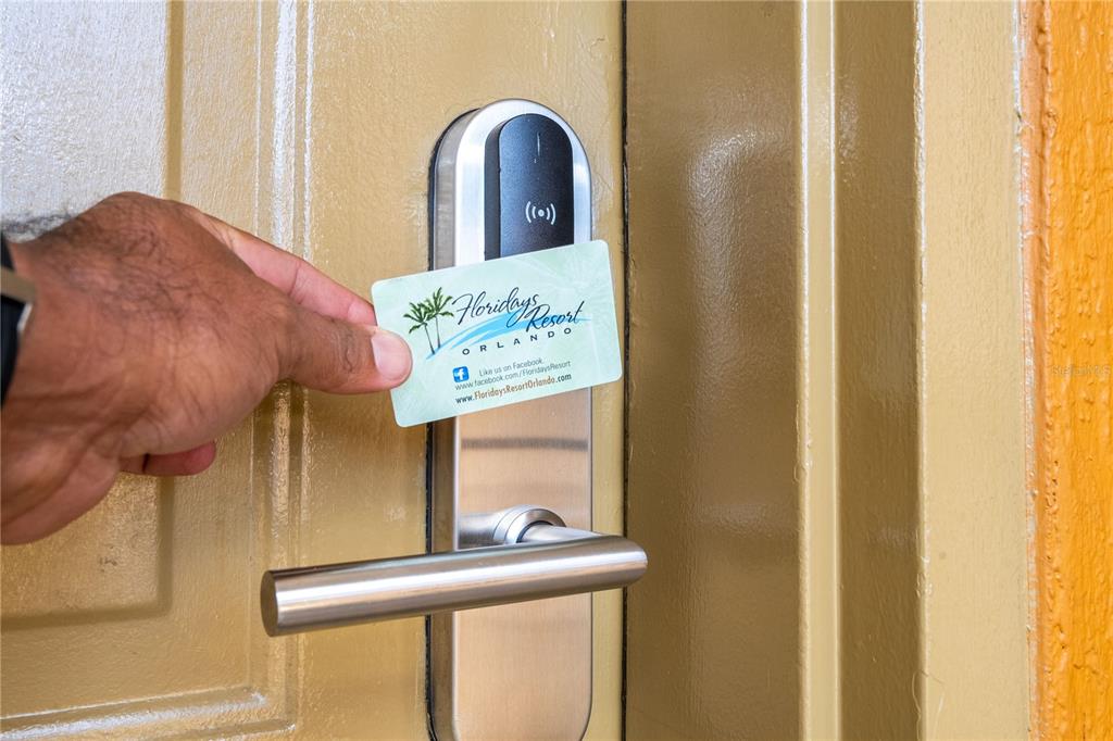 A hand holds a key card against an electronic lock on a tan door — 12527 FLORIDAYS RESORT DRIVE UNIT 611-E, ORLANDO, FL