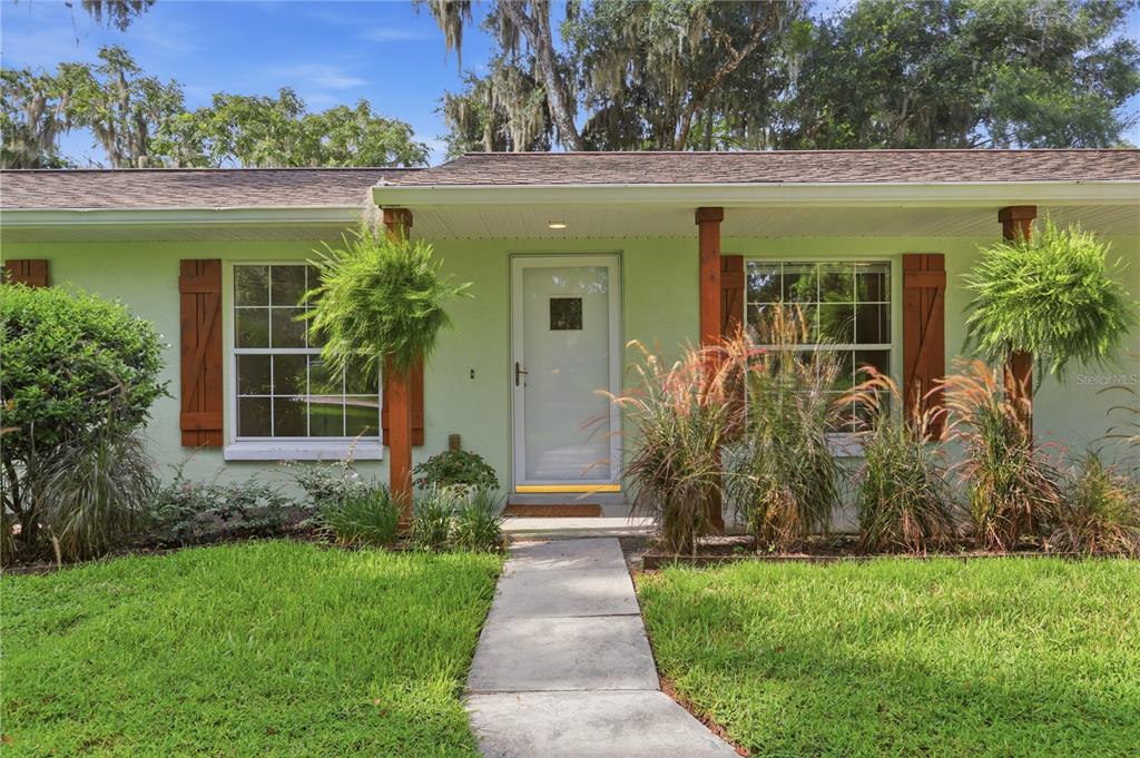 A light green house exterior features a front door, wooden posts, and hanging plants — 2020 LEMON STREET, DELAND, FL