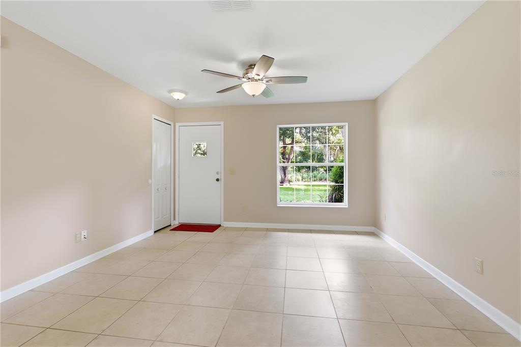 An empty room with beige walls, tile flooring, a ceiling fan, and a single window — 2020 LEMON STREET, DELAND, FL