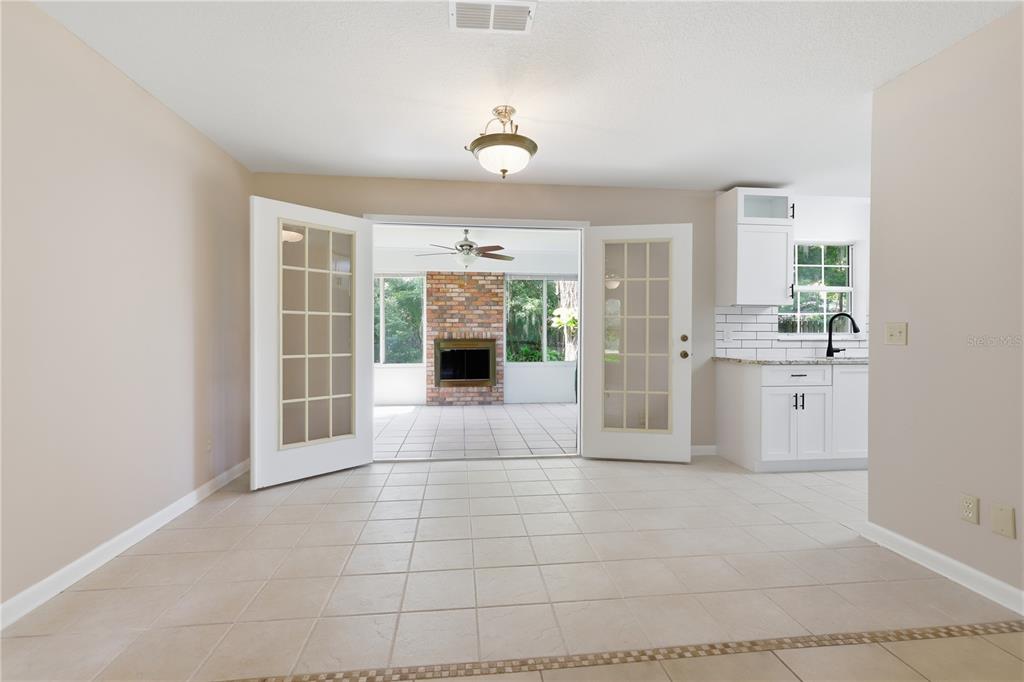 A dining area with tile floors opens through French doors to a screened porch with fireplace — 2020 LEMON STREET, DELAND, FL