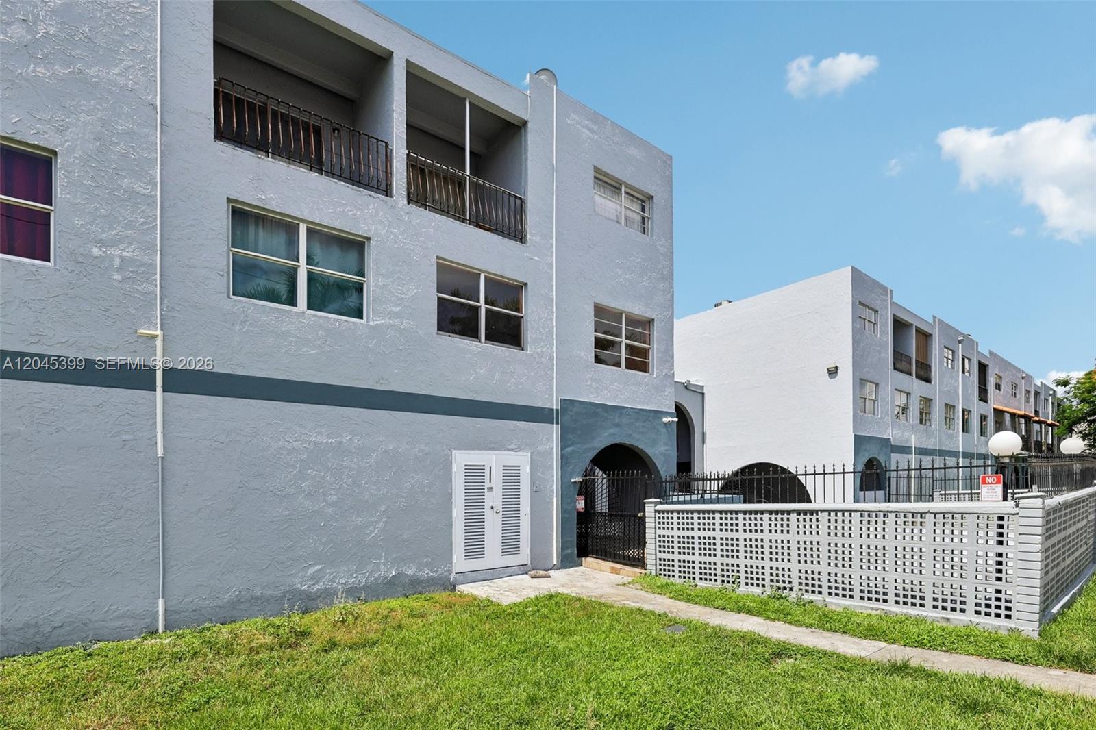 A multi-story apartment building features light gray stucco walls, balconies, and a decorative privacy wall — 1300 W 53rd St # 25, Hialeah FL 33012, HIALEAH, FL
