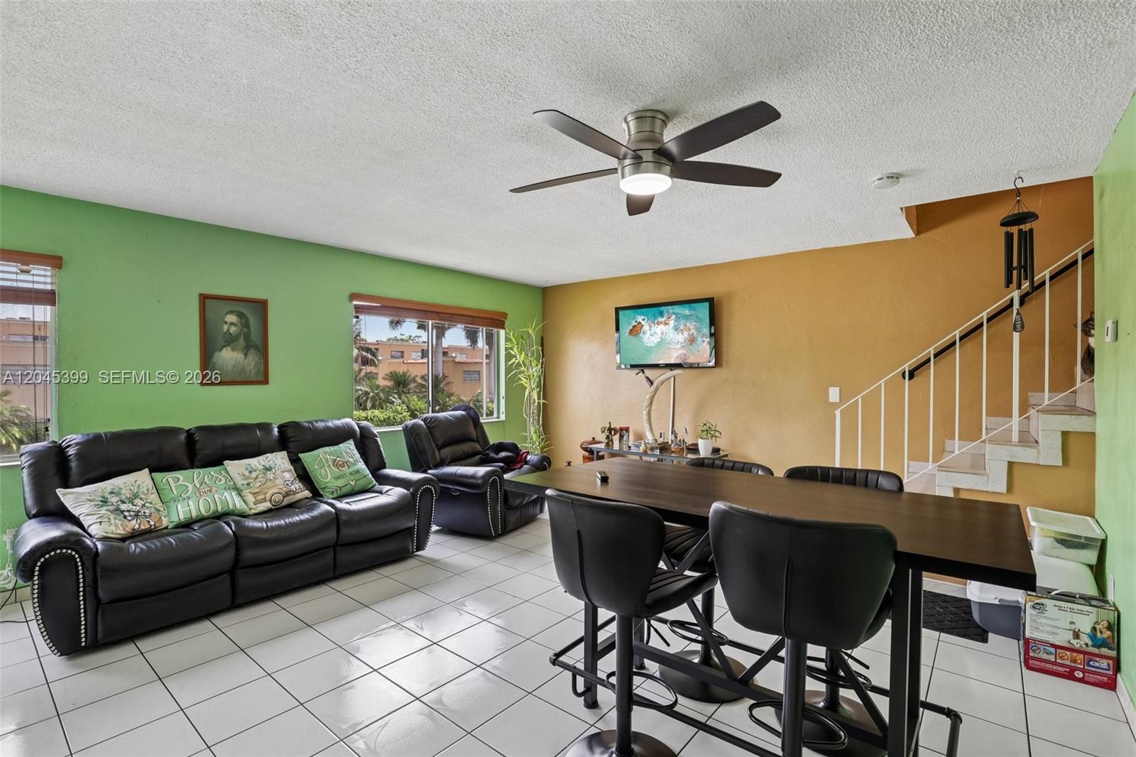 A living and dining area features green and tan walls, tile floors, and a staircase — 1300 W 53rd St # 25, Hialeah FL 33012, HIALEAH, FL