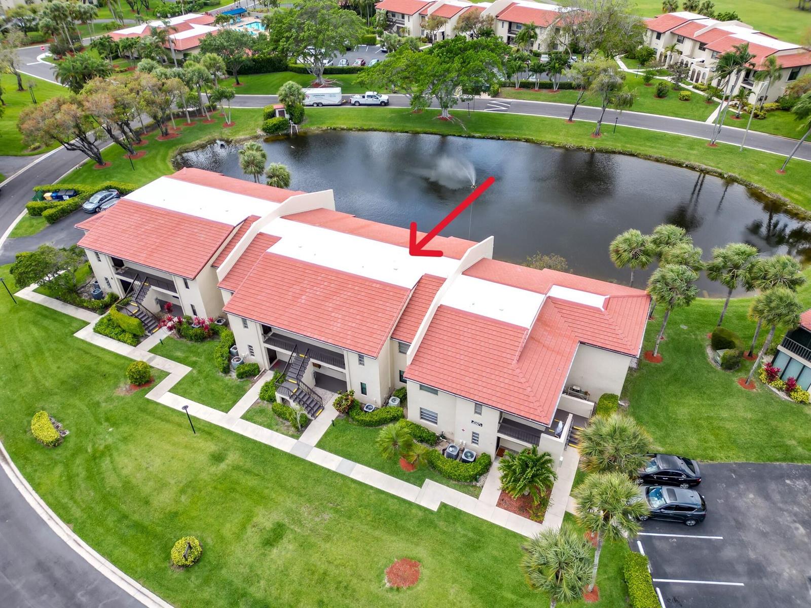 An aerial view shows a multi-unit residential building with a red tile roof and pond — 21218 Lago Circle # H, Boca Raton FL 33433, BOCA RATON, FL