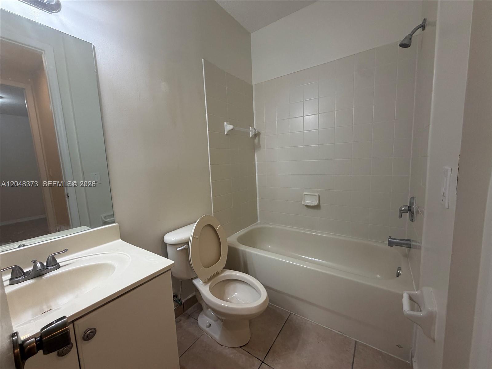 A bathroom features a vanity, a toilet, and a bathtub with a shower head — 666 NE 35th Ave, Homestead FL 33033, HOMESTEAD, FL