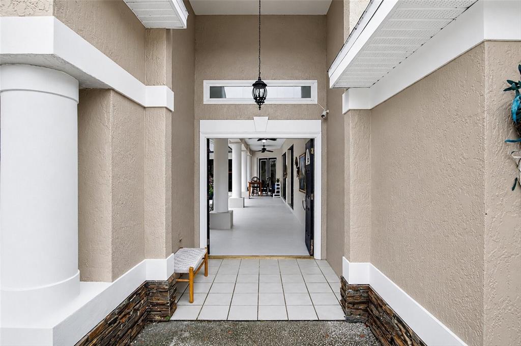 An outdoor entryway with a tiled floor leads through an open doorway to a covered patio — 9123 MAVIS ROAD, WEEKI WACHEE, FL