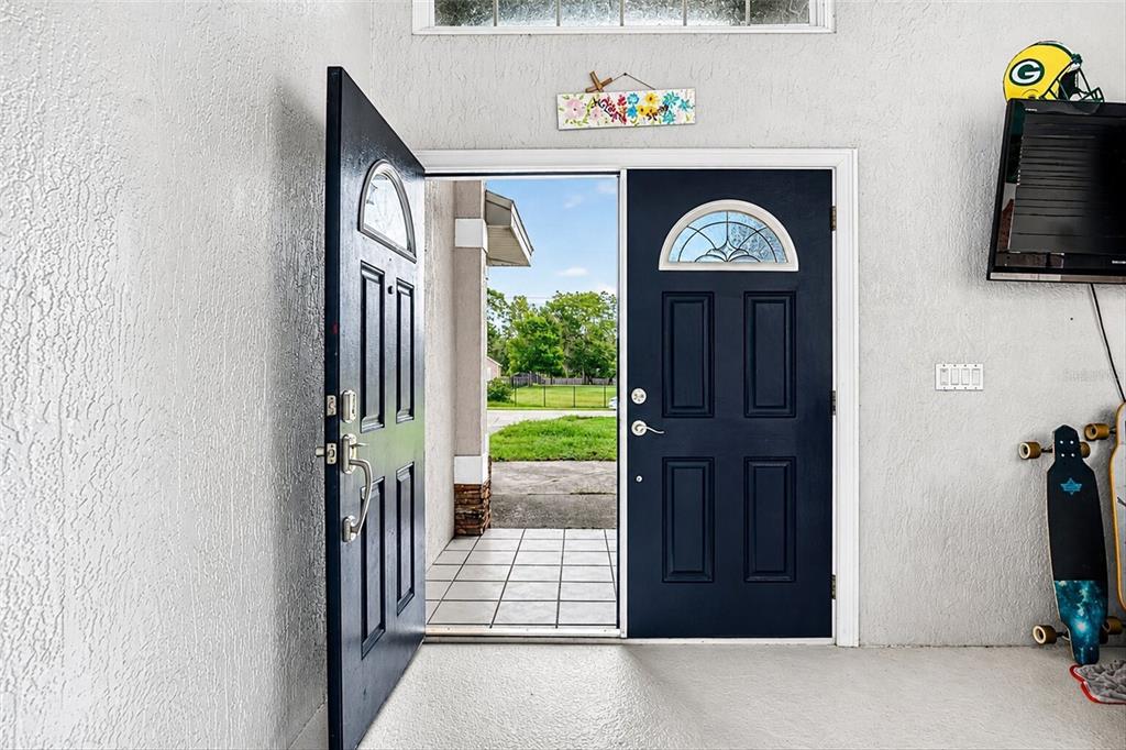 An open dark blue front door reveals a tiled entryway and a view of outdoors — 9123 MAVIS ROAD, WEEKI WACHEE, FL