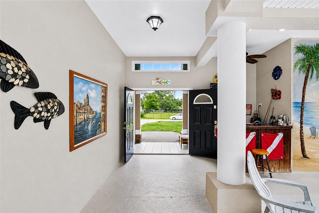 An entryway leads to an outdoor view, featuring wall art, a bar area, and tile flooring — 9123 MAVIS ROAD, WEEKI WACHEE, FL