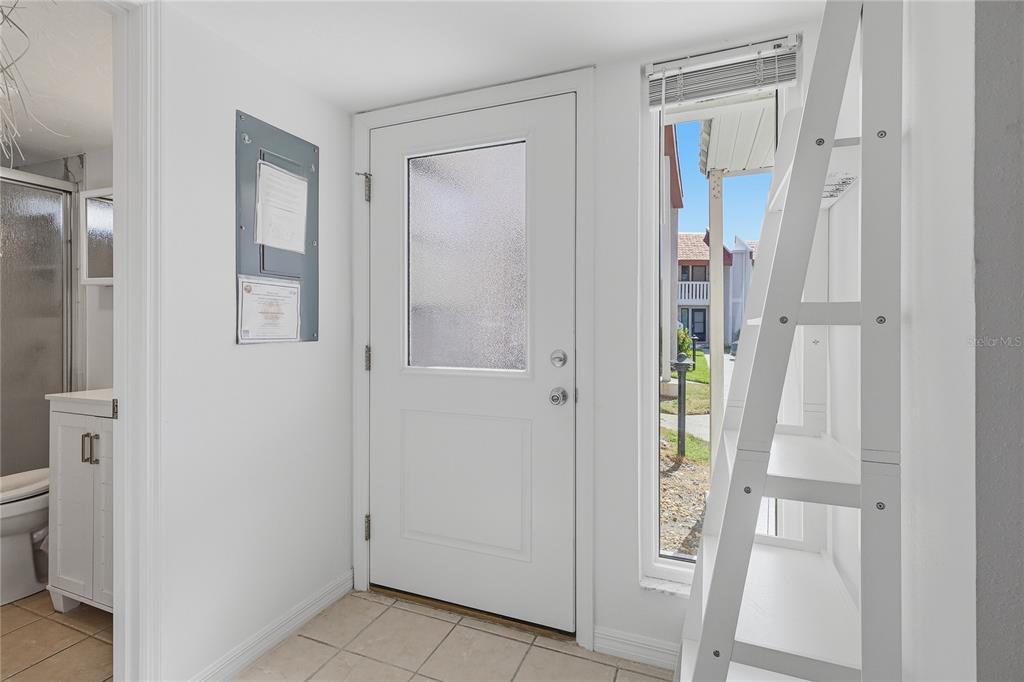 A white entryway with a tiled floor, a glass-paneled door, and a white ladder shelf — 1801 GULF DRIVE N UNIT 183, BRADENTON BEACH, FL