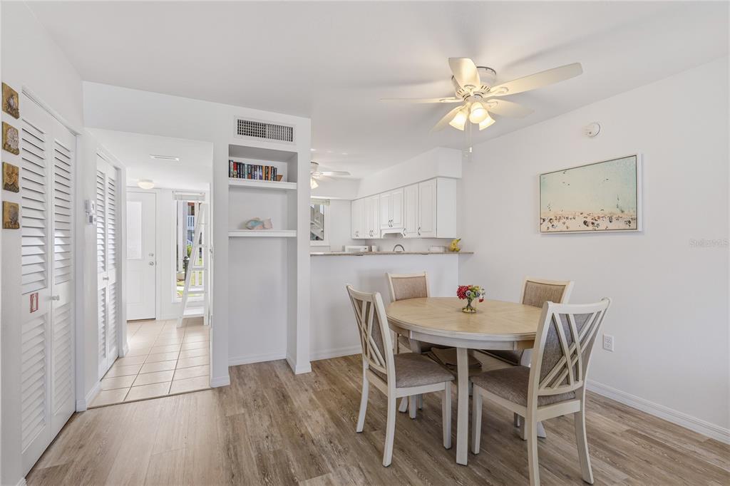 A dining area features a round wooden table with four chairs and an adjacent kitchen — 1801 GULF DRIVE N UNIT 183, BRADENTON BEACH, FL