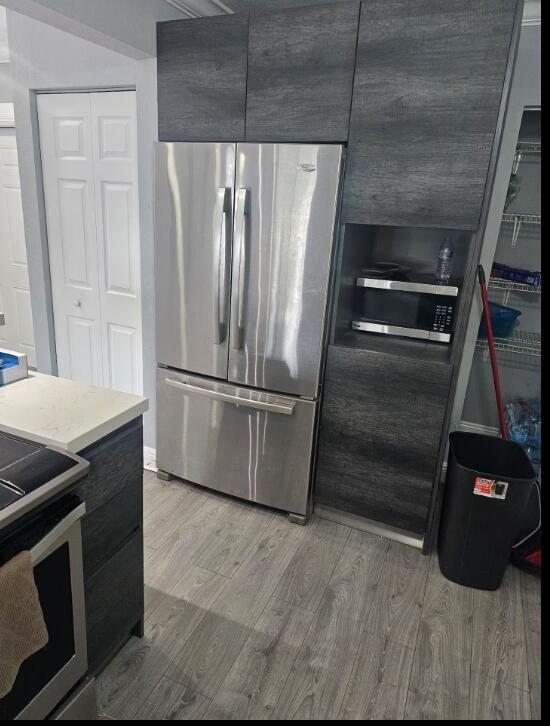 A kitchen features a stainless steel refrigerator next to dark wood cabinetry with a built-in microwave — 750 SW 55th Avenue, Margate FL 33068, MARGATE, FL