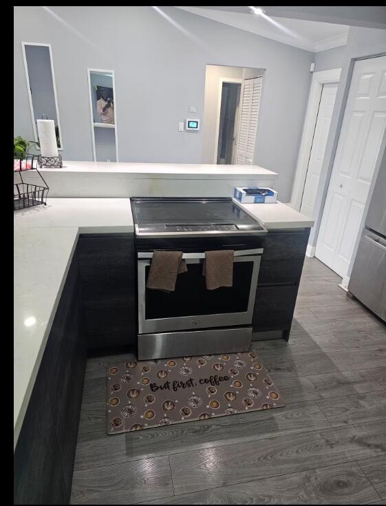 A kitchen features dark cabinets, white countertops, a stainless steel stove, and wood-look flooring — 750 SW 55th Avenue, Margate FL 33068, MARGATE, FL