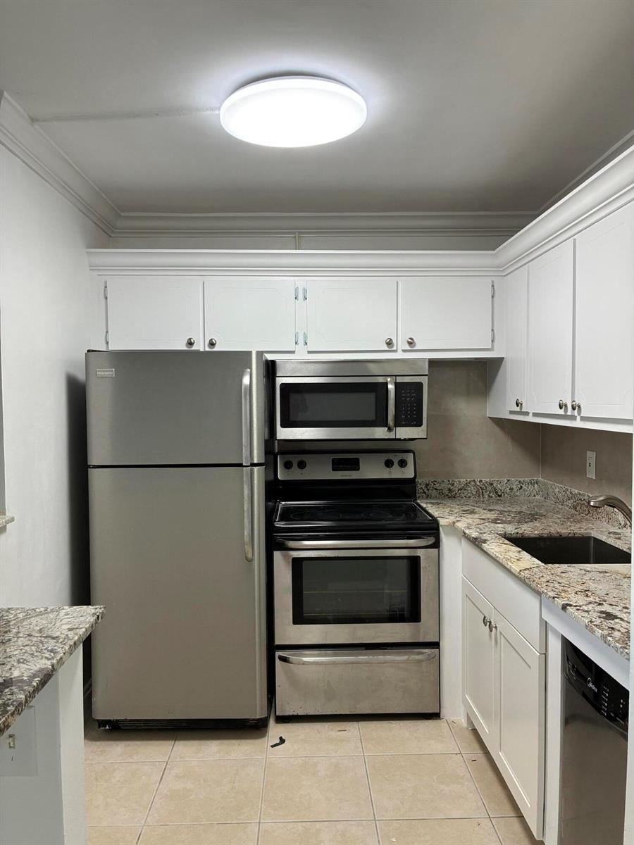 A kitchen featuring stainless steel appliances, white cabinetry, and granite countertops — 650 Horizons Avenue E # 107, Boynton Beach FL 33435, BOYNTON BEACH, FL
