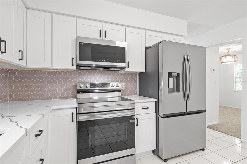 A modern kitchen features white cabinets, stainless steel appliances, and a hexagonal tile backsplash — 776 MOCKINGBIRD LANE, DELAND, FL