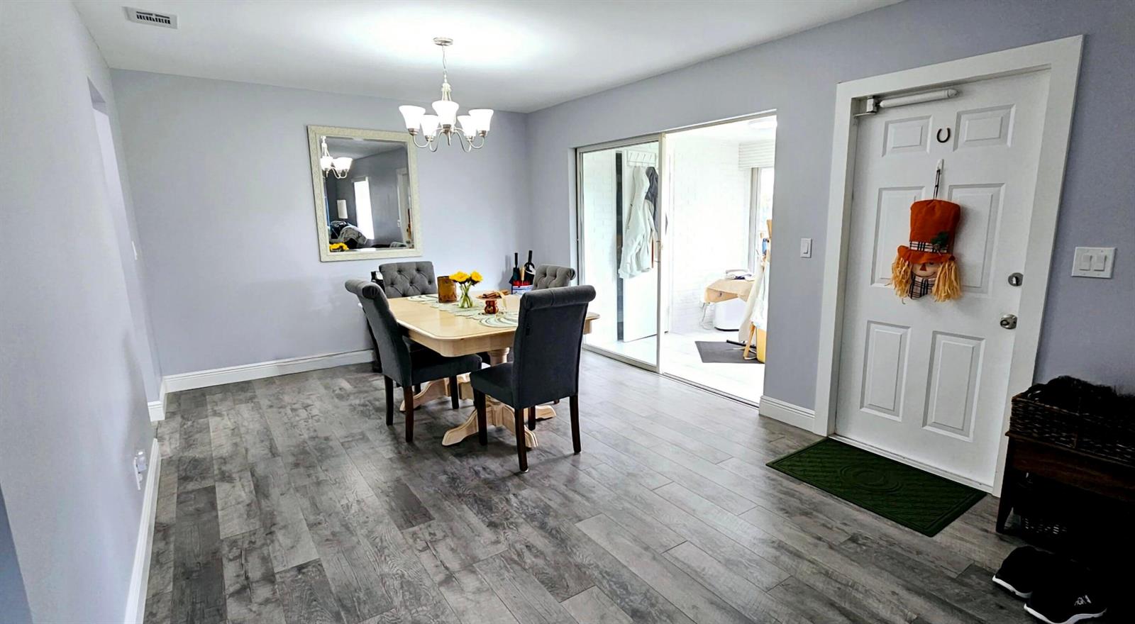 A dining room with gray walls, wood-look flooring, a chandelier, and a sliding glass door — 10126 S 44th Terrace S, Boynton Beach FL 33436, BOYNTON BEACH, FL