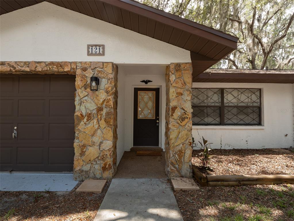 The exterior of a house features a stone-faced entryway, a garage, and a front window — 121 SERENA CIRCLE, MELROSE, FL