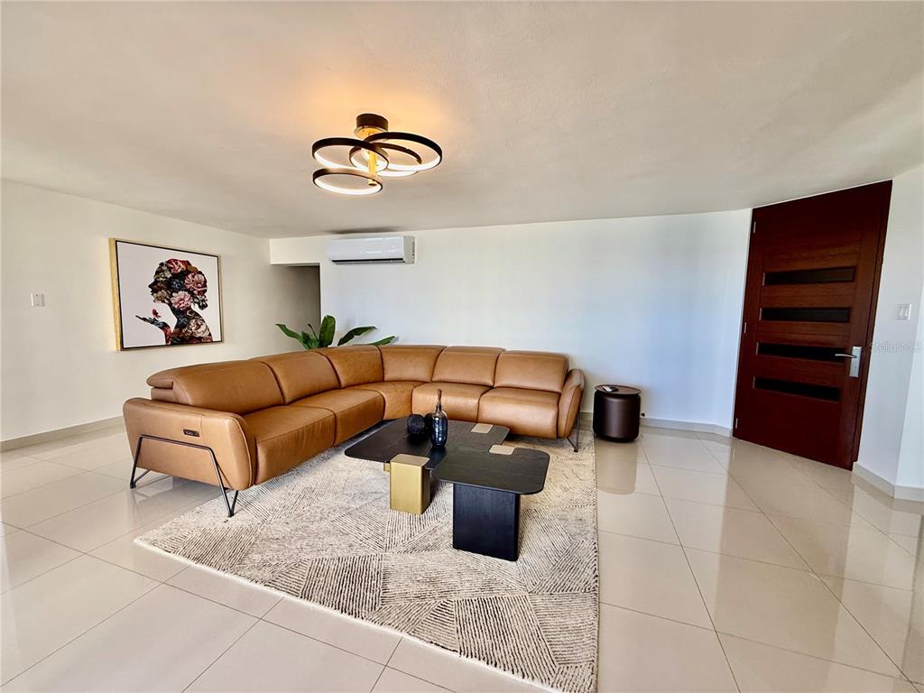 A living room features a tan leather sectional sofa, a modern coffee table, and a rug — 1510 ASHFORD AVENUE UNIT 7E, SAN JUAN, PR