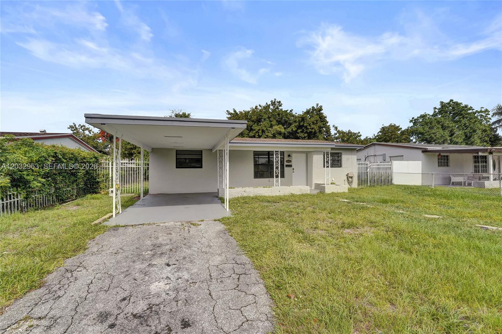 A single-story house features a flat roof, a carport, and a cracked concrete driveway — 1140 N 74th Way, Hollywood FL 33024, HOLLYWOOD, FL