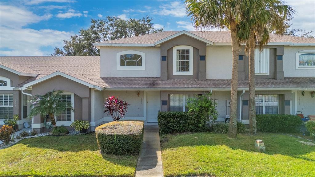A two-story townhouse exterior features a beige stucco facade, a walkway, and a palm tree — 1220 GARDEN ISLE COURT, ORLANDO, FL