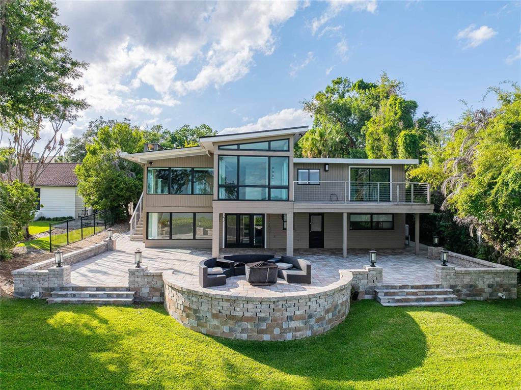 A two-story modern house features a stone patio with a curved wall and fire pit — 7 LAKE HOLLINGSWORTH DRIVE, LAKELAND, FL