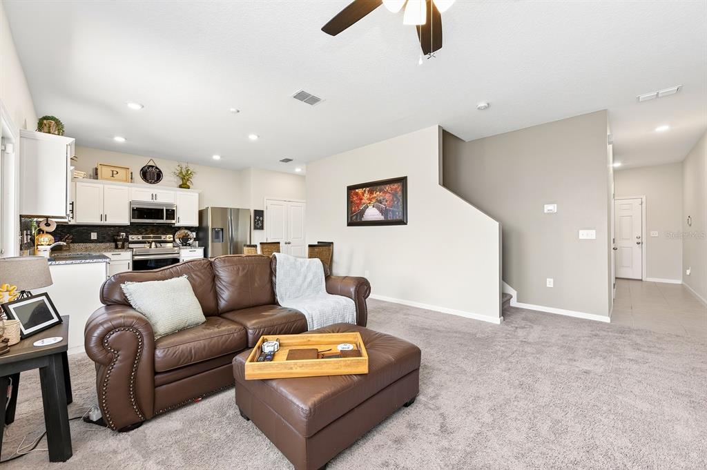 A living room with a brown leather sofa and ottoman opens into a kitchen area — 1961 HEMINGWAY CIRCLE, GROVELAND, FL