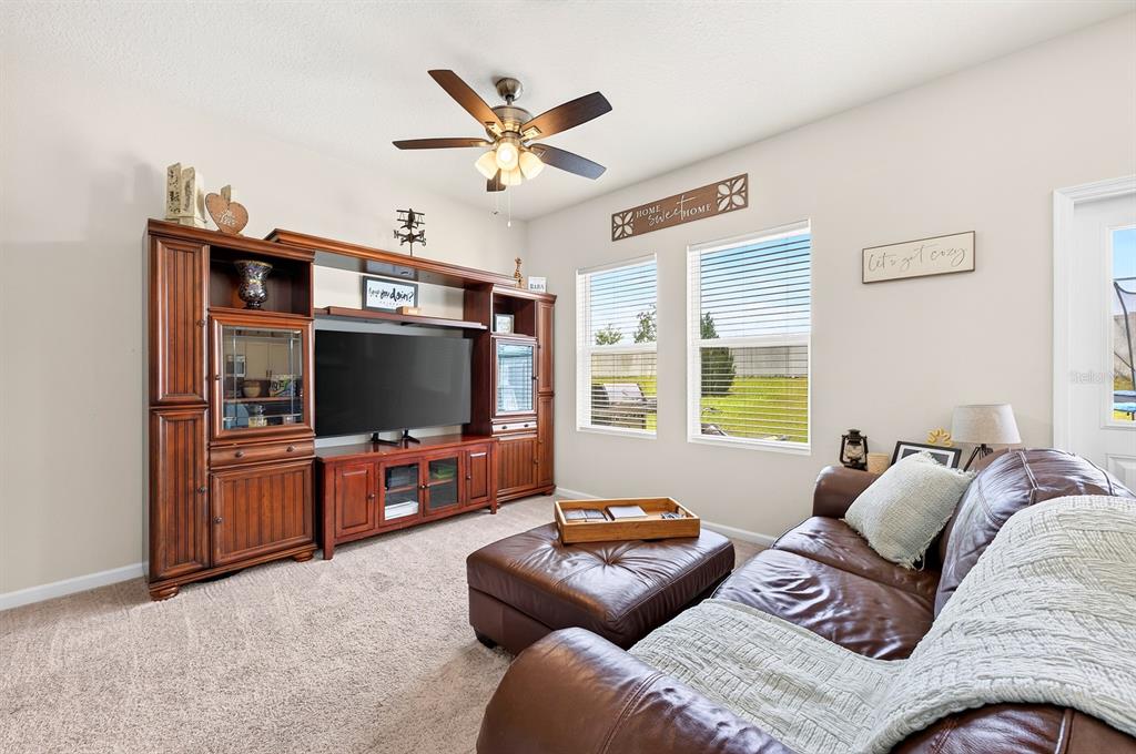 A living room features a large wooden entertainment center, brown leather sofa, and ceiling fan — 1961 HEMINGWAY CIRCLE, GROVELAND, FL