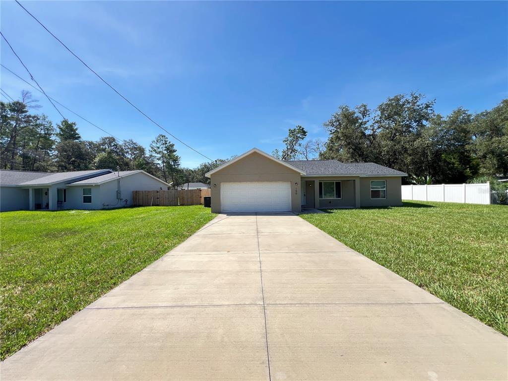 A single-story house with a beige exterior, a two-car garage, and a concrete driveway — 190 FISHER WAY, OCKLAWAHA, FL
