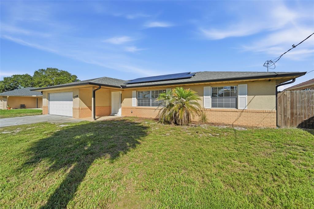 A single-story house with a brick and stucco exterior, a garage, and solar panels — 1289 DANDELION DRIVE, DELTONA, FL
