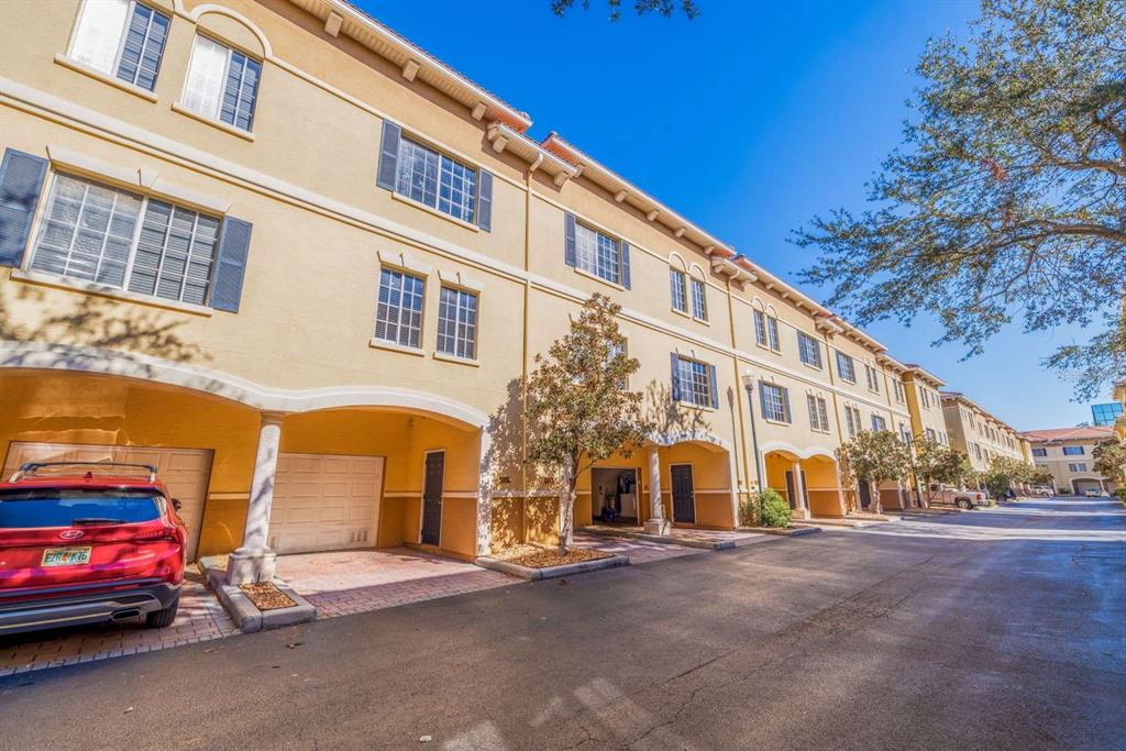 A row of multi-story townhomes with beige stucco facades, arched entryways, and attached garages — 5252 W KENNEDY BOULEVARD, TAMPA, FL