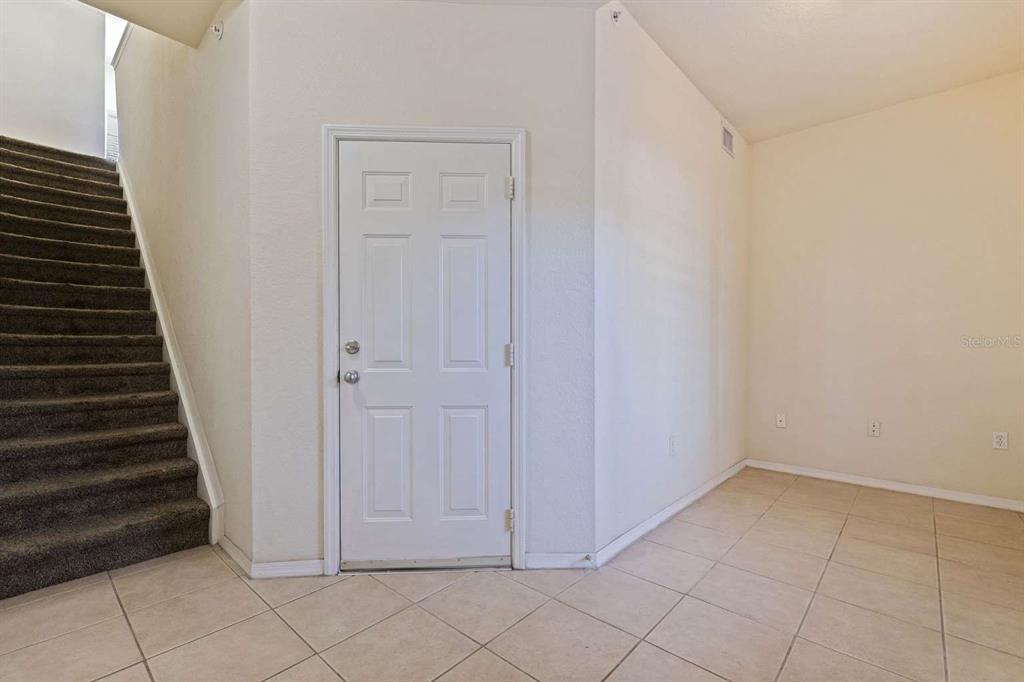 An interior view shows a carpeted staircase next to a white door and tiled floor — 5252 W KENNEDY BOULEVARD, TAMPA, FL