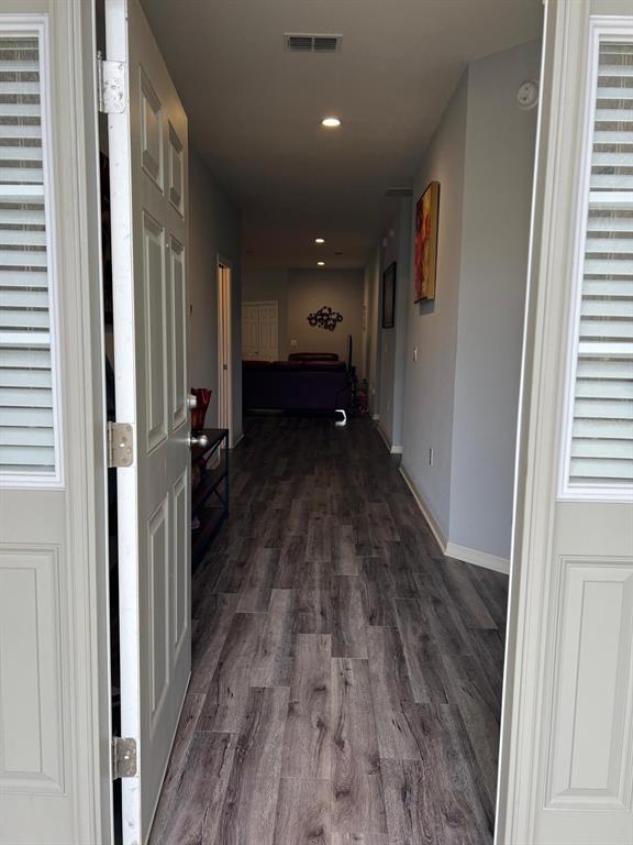 A view from an open doorway looking down a hallway with wood-look flooring toward a living room — 446 GLENKIRK WAY, LAKE ALFRED, FL
